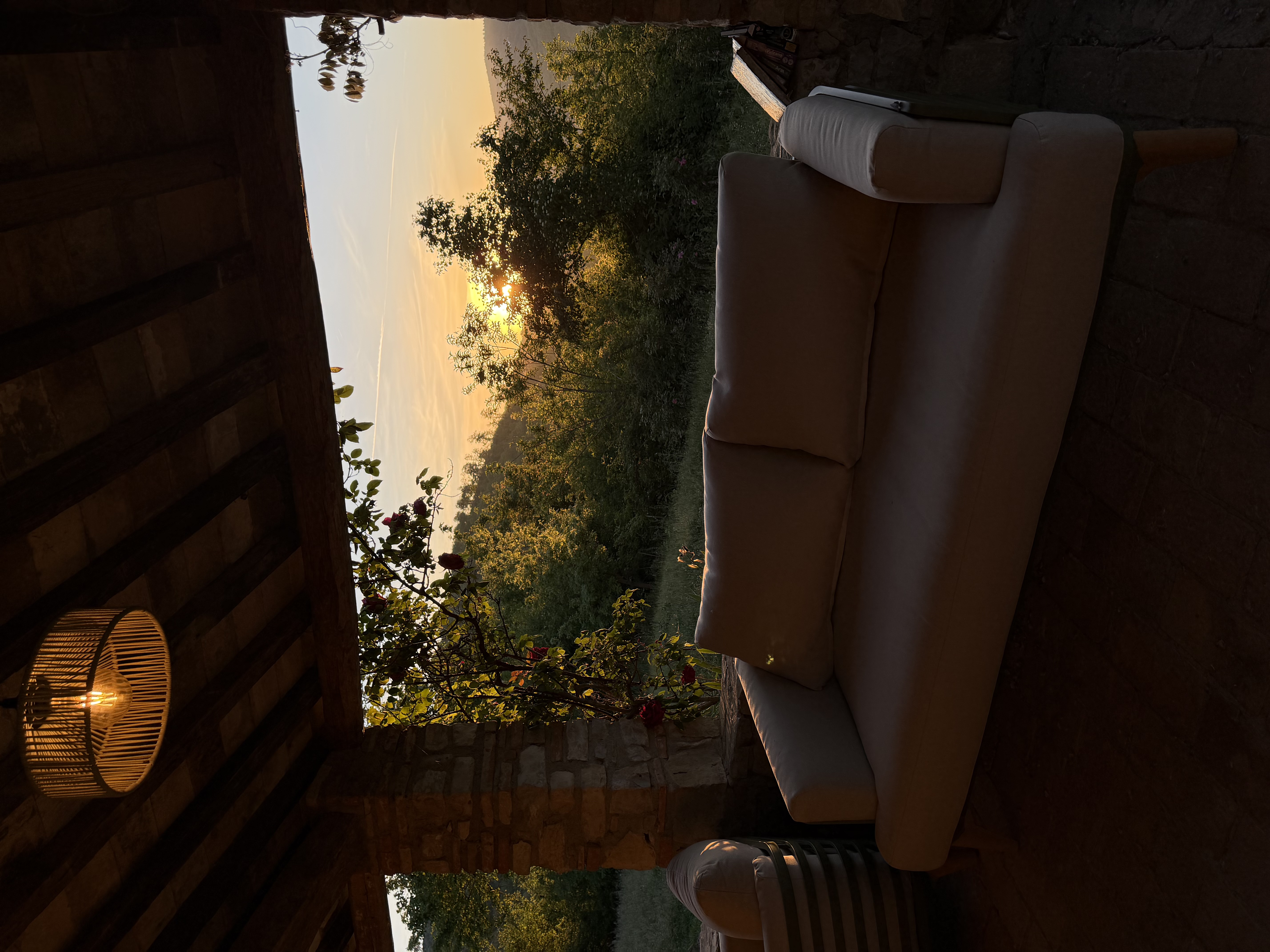 Covered outdoor lounge at sunset with bamboo pendant lamp and sofa